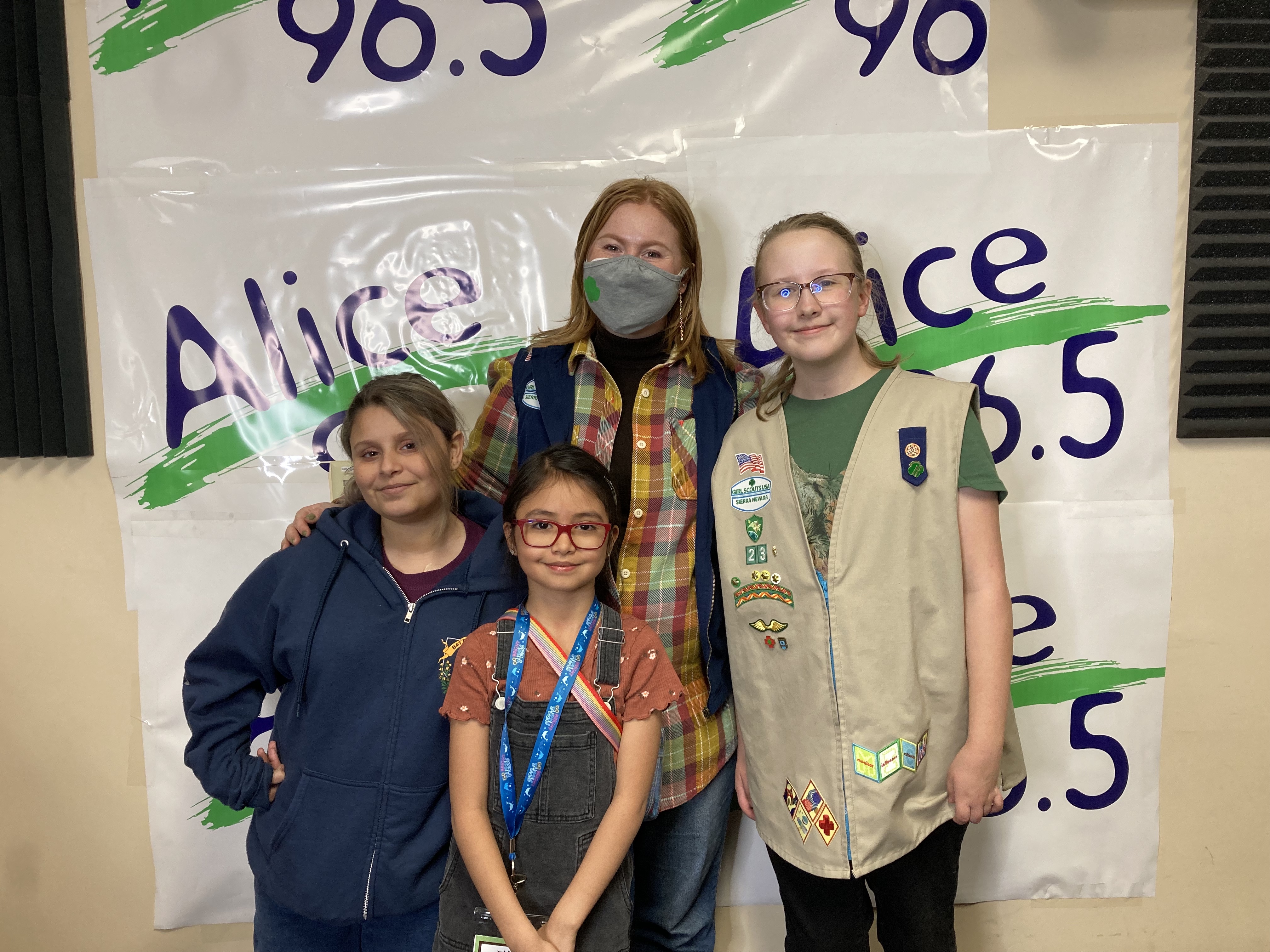 Audrey and 3 girl scouts stand in front of the Alice Radio sign 