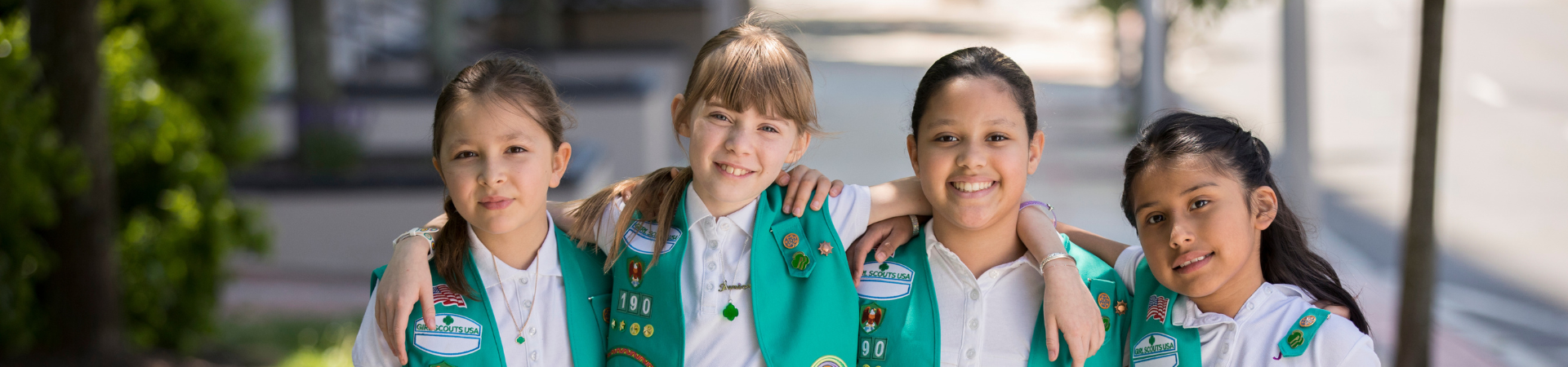  four junior girl scouts smiling with their arms around each other 