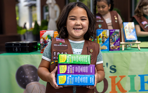 Girl Scout holding boxes of cookies